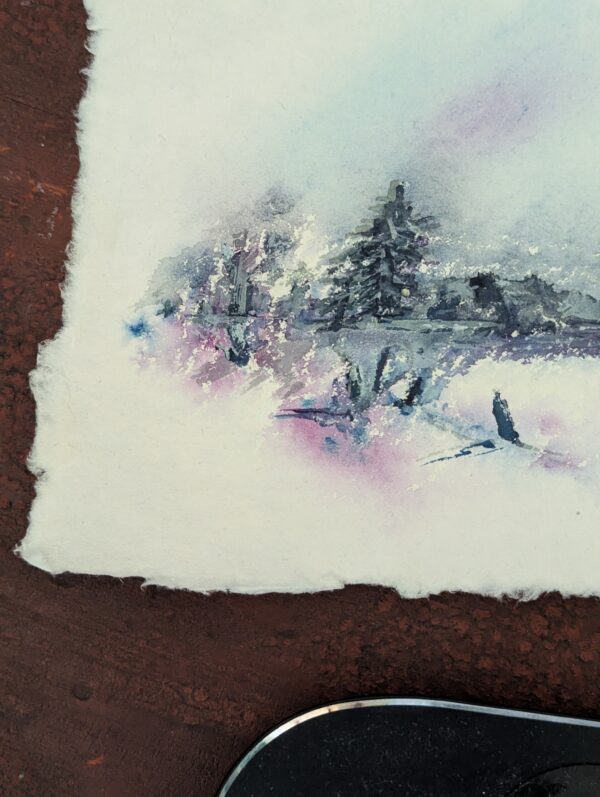 Close up of deckled edges of the watercolour paper this of this winter landscapes with pine trees and mountains.
